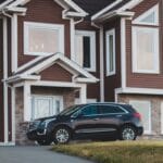 black suv parked in front of white wooden house