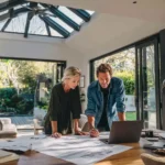 Architect and homeowner reviewing blueprints for window and door installation inside a stylish California home during the planning and permit process.